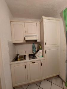 una piccola cucina con armadi bianchi e lavandino di Appartamento a Punta Asfodeli a Porto Rotondo