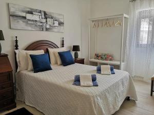 ein Schlafzimmer mit einem großen Bett mit blauen Kissen darauf in der Unterkunft Casa da Zira II - Vista de Mar in Nazaré