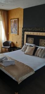 um quarto com uma grande cama branca e uma cadeira em Apartmani President I em Banja Luka