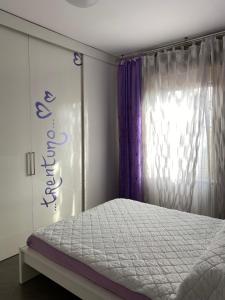 a bedroom with a bed and a window with purple curtains at Petit place incantevole a due passi da Milano! in Cologno Monzese
