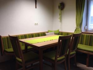 una mesa y sillas en un restaurante con cojines verdes en Ferienwohnung Lechner, en Karres