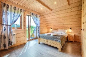 a bedroom with a bed in a log cabin at Cicha Przystań Dzianisz z sauną i gorącą balią in Dzianisz