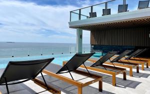 a row of chairs sitting on a patio overlooking the ocean at The Elysium Prațumnak Pattaya - By SHG in Pattaya South