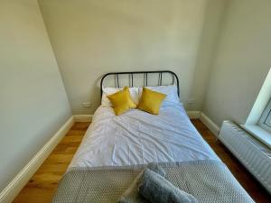 a bed with yellow pillows in a small room at Cosy 1 bedroom flat! in London