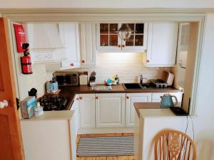 a kitchen with white cabinets and a stove top oven at The Nautical Nest in the heart of Dartmouth in Dartmouth