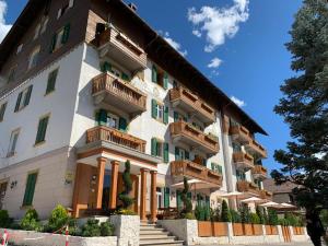 a large white building with balconies on it at Hotel Serena Cortina in Cortina dʼAmpezzo