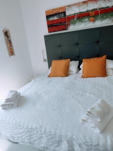 1 cama grande con almohadas de color naranja y sábanas blancas en Torreguadiaro Villa - 2 mins walk from the bars and restaurants en San Roque