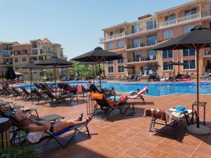 a group of people laying in lawn chairs by a pool at Hacienda Beach Apartment mit Meerblick in Sozopol