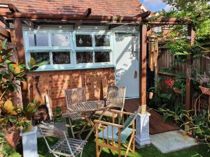 a patio with chairs and a table and a building at Lotus Pod House Homestay in Horsell