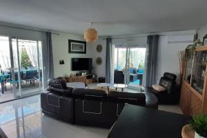 a living room with black leather furniture and a television at BASSIN D'ARCACHON, Maison vacances climatisée au calme, proche plage in Lanton