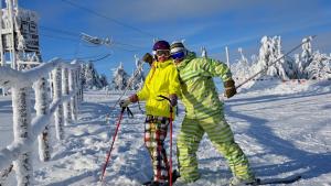 twee mensen op ski's in de sneeuw bij Penzión Zlatny Potok in Mutné