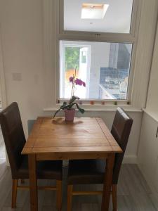 a wooden table with chairs and a potted plant on it at London Road Flats - Free WIFI, washing machine, smart TV, easy access to A50 in Derby