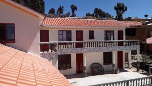 a white house with a balcony and a roof at LA KANTUTA in Comunidad Yumani