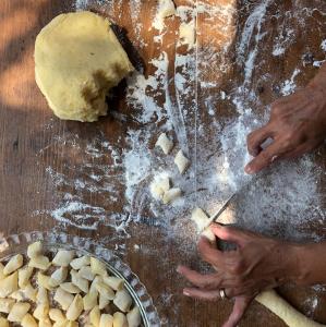 a person cutting up a dough on a table at Terecate Experimental Relais in Melendugno