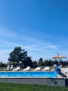 a swimming pool with lounge chairs and an umbrella at Ostrovia - pokoje nad morzem in Ostrowo