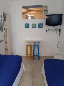 a room with two beds and a table and a tv at Good Vibes in Praia Grande