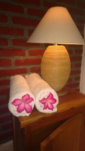 three towels with flowers on a table next to a lamp at Bungalow And Restaurant Anda in Kuta Lombok
