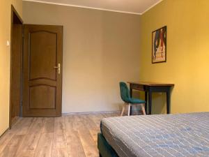 a bedroom with a bed and a chair and a table at Komfortowy Apartament blisko plaży in Gdańsk