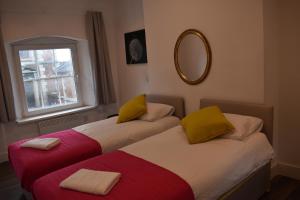 two beds in a room with a mirror and a window at Florence House in Denbigh