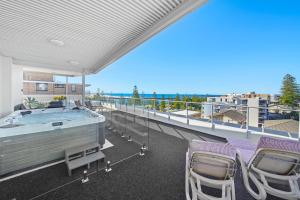 uma grande varanda com uma banheira de hidromassagem e cadeiras em Macquarie Waters Boutique Apartment Hotel em Port Macquarie