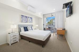 a bedroom with a bed and a desk with a television at Macquarie Waters Boutique Apartment Hotel in Port Macquarie +23 photos