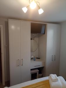1 dormitorio con armario blanco y escritorio en 4TheDome- Deluxe ground floor apartment opposite the sea en Barton on Sea