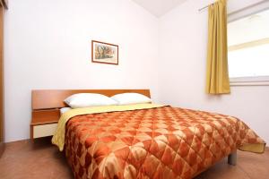 1 dormitorio con 1 cama con edredón de naranja y ventana en Apartment Baska Voda 10027a, en Baška Voda