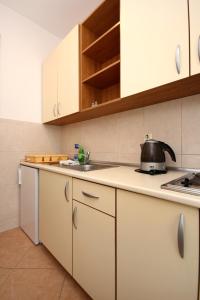 cocina con armarios blancos y tetera en la encimera en Apartment Baska Voda 10027a, en Baška Voda