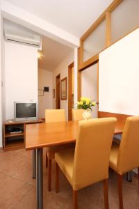 comedor con mesa de madera y sillas amarillas en Apartment Baska Voda 10027a, en Baška Voda