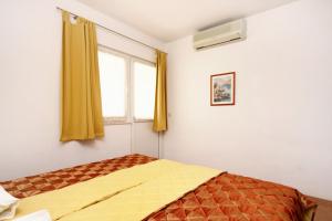 um quarto com uma cama com cortinas amarelas e uma janela em Apartment Baska Voda 10027c em Baska Voda