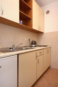 uma cozinha com armários brancos e um lavatório em Apartment Baska Voda 10027c em Baska Voda