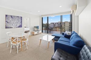 sala de estar con sofá azul y mesa en Macquarie Waters Boutique Apartment Hotel en Port Macquarie