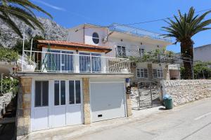 ジヴォゴシュチェにあるApartments with a parking space Zivogosce - Porat, Makarska - 10032の白いガレージドアとバルコニーが備わる家