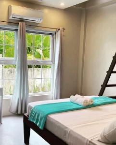 a bedroom with a bed and two windows at TeSario Retreat in General Luna