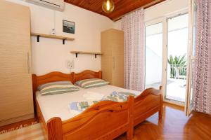 a bedroom with a wooden bed and a large window at Apartments with parking space Zivogosce - Porat, Makarska - 10032 in Živogošće