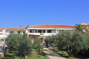 une grande maison blanche avec des arbres devant elle dans l'établissement Apartments with a parking space Povljana, Pag - 9405, à Povljana