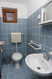 a blue tiled bathroom with a toilet and a sink at Apartment Igrane 10033a in Igrane