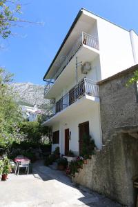 a white house with a balcony and a table at Apartments by the sea Igrane, Makarska - 10033 in Igrane