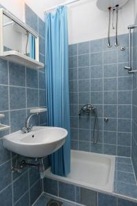 W wyłożonej niebieskimi kafelkami łazience znajduje się umywalka i prysznic. w obiekcie Apartments by the sea Igrane, Makarska - 10033 w mieście Igrane