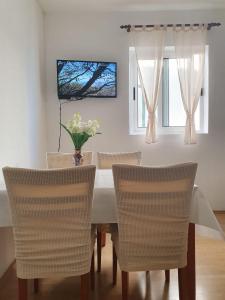 stół jadalny z krzesłami i wazonem kwiatów na nim w obiekcie Apartments by the sea Igrane, Makarska - 10033 w mieście Igrane
