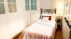 a bedroom with a bed with white sheets and red pillows at Sestao, Vivienda Turística Renovada con Terraza y WIFI in Sestao