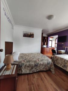 a bedroom with two beds and a table with a lamp at Casatodosantos in Cuenca