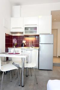 a white kitchen with a table and white appliances at Apartments by the sea Duce, Omis - 10304 in Duće
