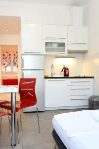 Apartment Duce 10304b في دوسيه: مطبخ فيه دواليب بيضاء وطاولة وكراسي حمراء