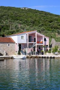 a pink house on the shore of a body of water at Apartments by the sea Zuronja, Peljesac - 10123 in Brijesta