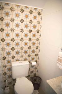 a bathroom with a toilet and a tiled wall at Las Gardenias in Florianópolis