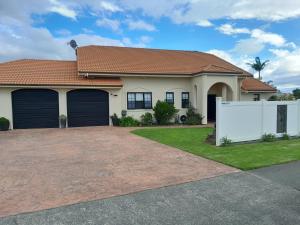 a house with two garage doors and a driveway at Moana Vista in One Tree Point