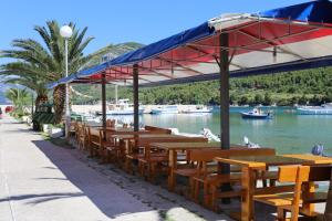 a row of wooden tables and benches next to a river at Apartments by the sea Zuljana, Peljesac - 10218 in Žuljana