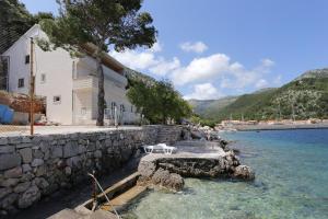 a stone wall next to a building and the water at Apartments by the sea Trstenik, Peljesac - 10110 in Trstenik