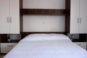 a bedroom with a bed with white sheets and cabinets at Apartment Drace 10127b in Drače